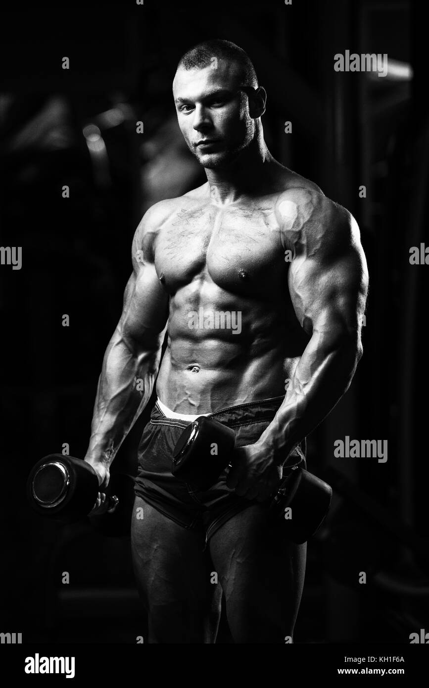 Man Working Out Biceps In A Gym - Dumbbell Concentration Curls Stock Photo