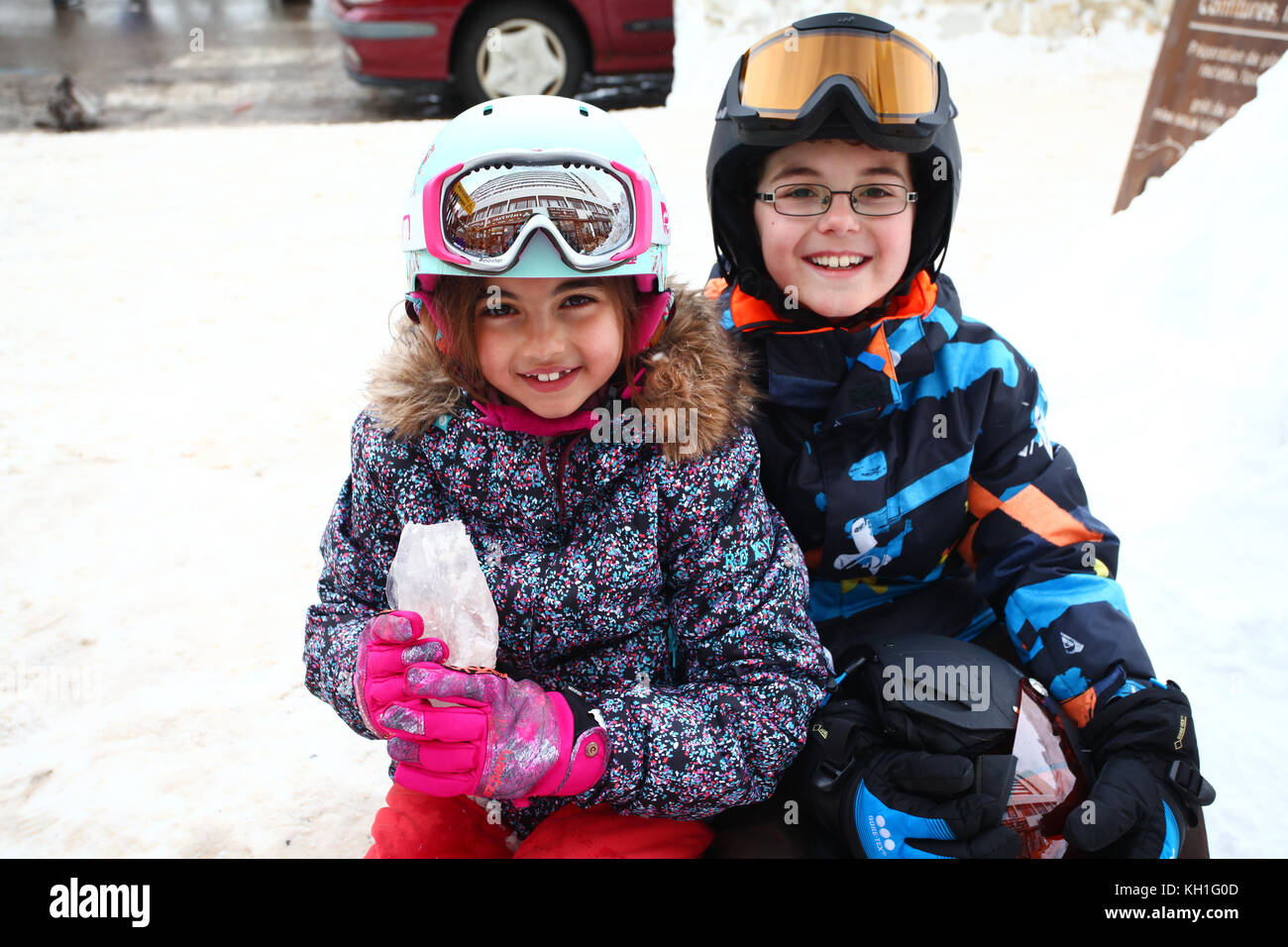kids in the snow wearing ski suits, helmets and goggles Stock Photo