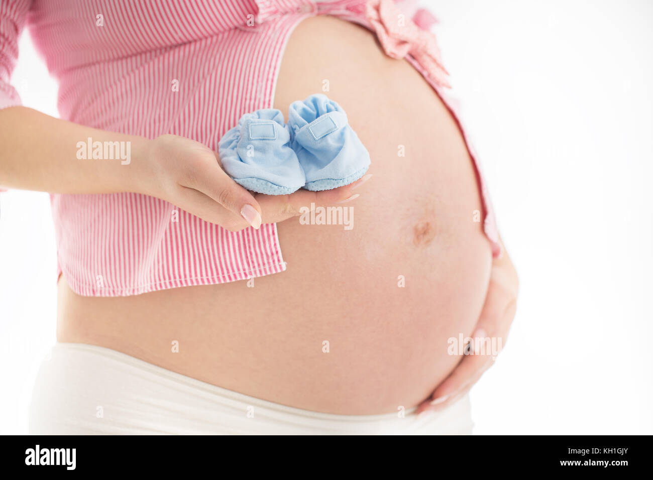 Small shoes for the unborn baby in the belly of pregnant woman Stock Photo
