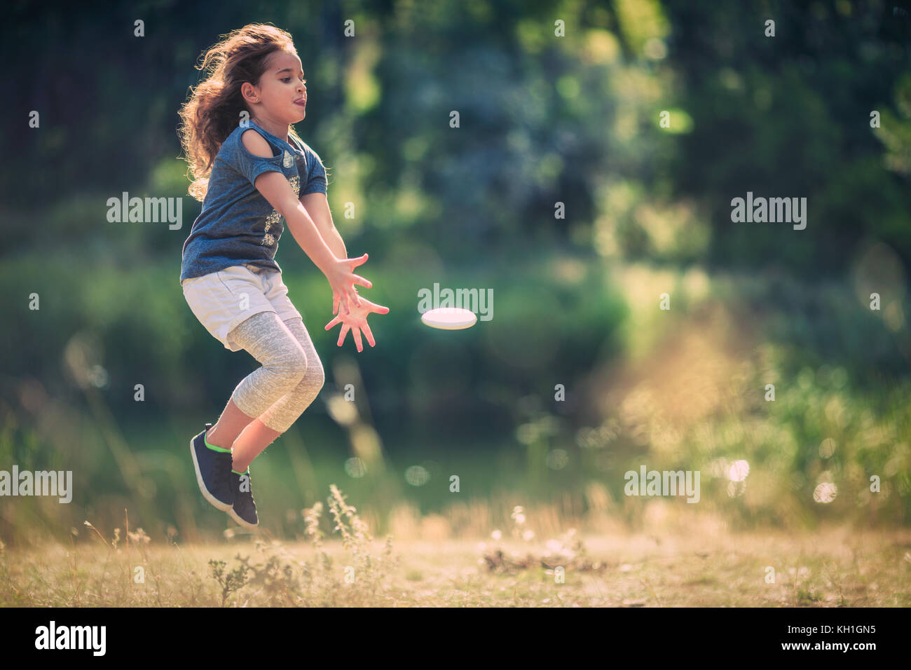 Happy little girl enjoying the nature and the sunny day in the park Stock Photo