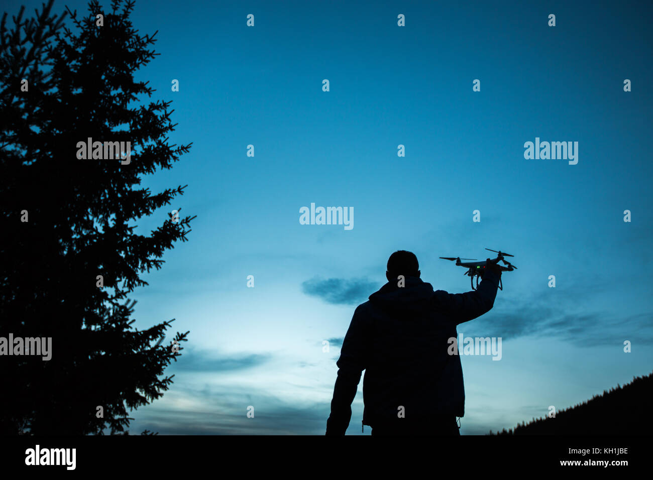 Man holding a drone for aerial photography. Silhouette against the sunset sky Stock Photo
