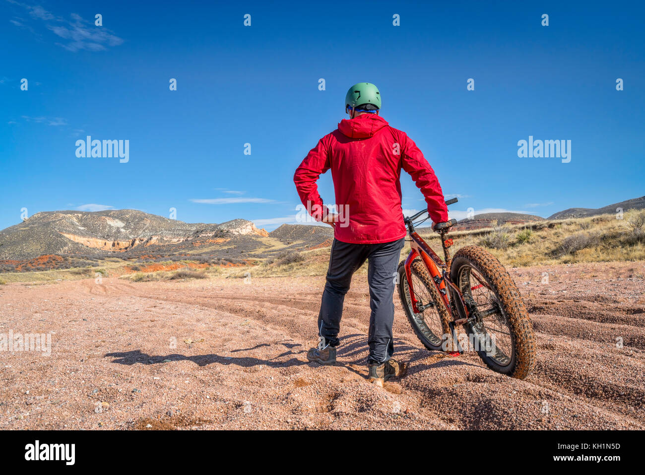 a tired male cyclist with a fat bike contemplating a tough and long ride through deep gravel on Big Hole Wash Trail in Red Mountain Open Space, Colora Stock Photo