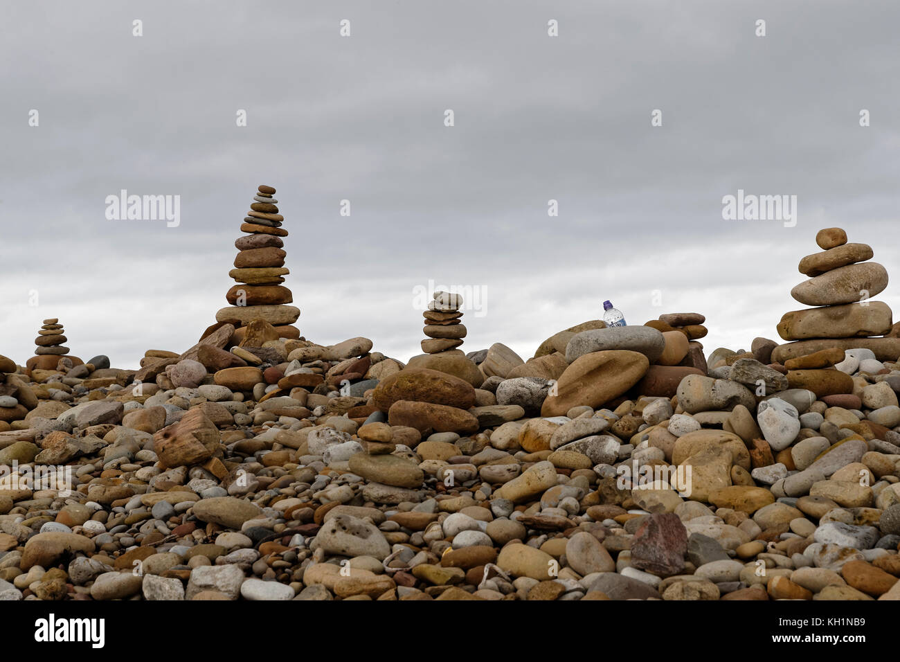 Man made stacks of stone / cairns (& a plastic bottle) lining the east beach of Holy Island