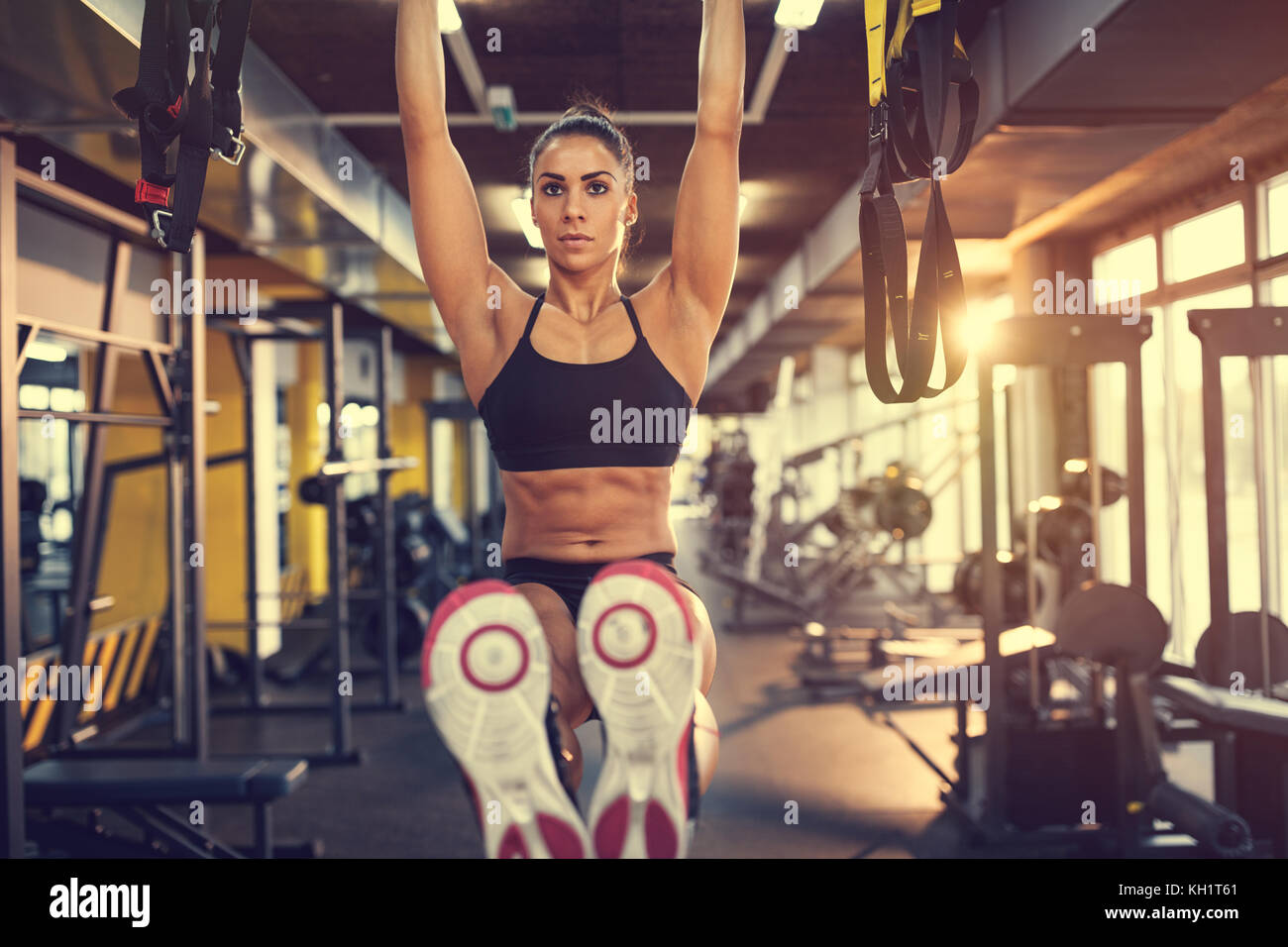 Girl on training in gym pulls up on bar and exercises six pack Stock Photo  - Alamy