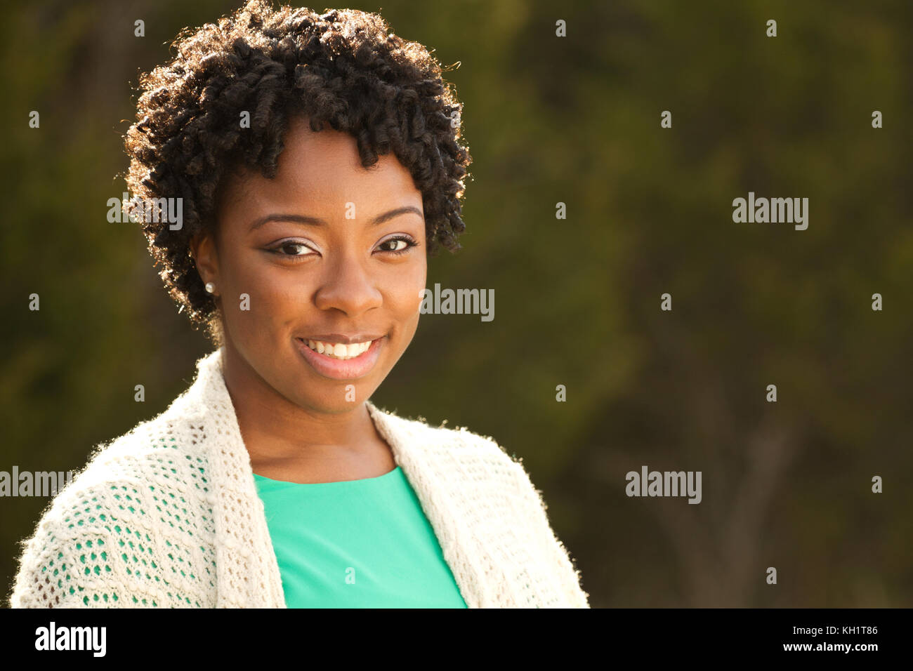African American woman with curly hair smiling outside Stock Photo - Alamy