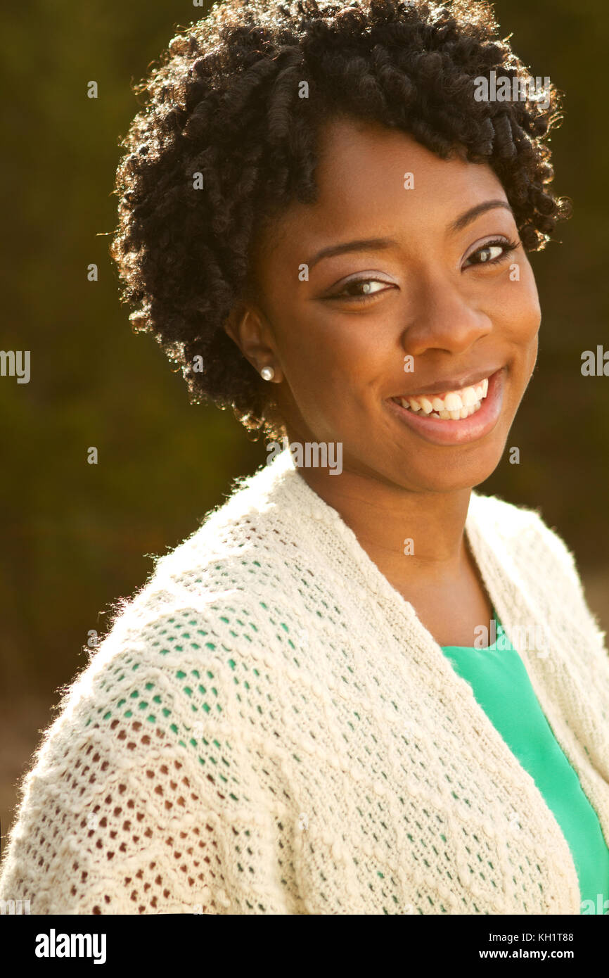 African American woman with curly hair smiling outside Stock Photo - Alamy