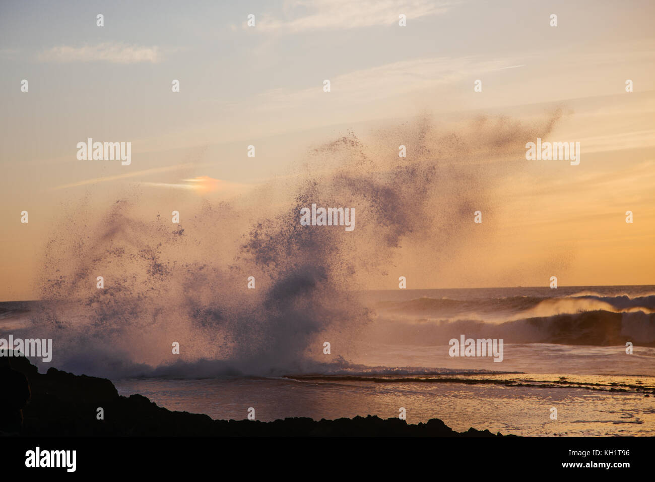 Big waves hitting the rocks as the golden sun sets on the coast of Hay El Fath, Rabat. Morocco Stock Photo