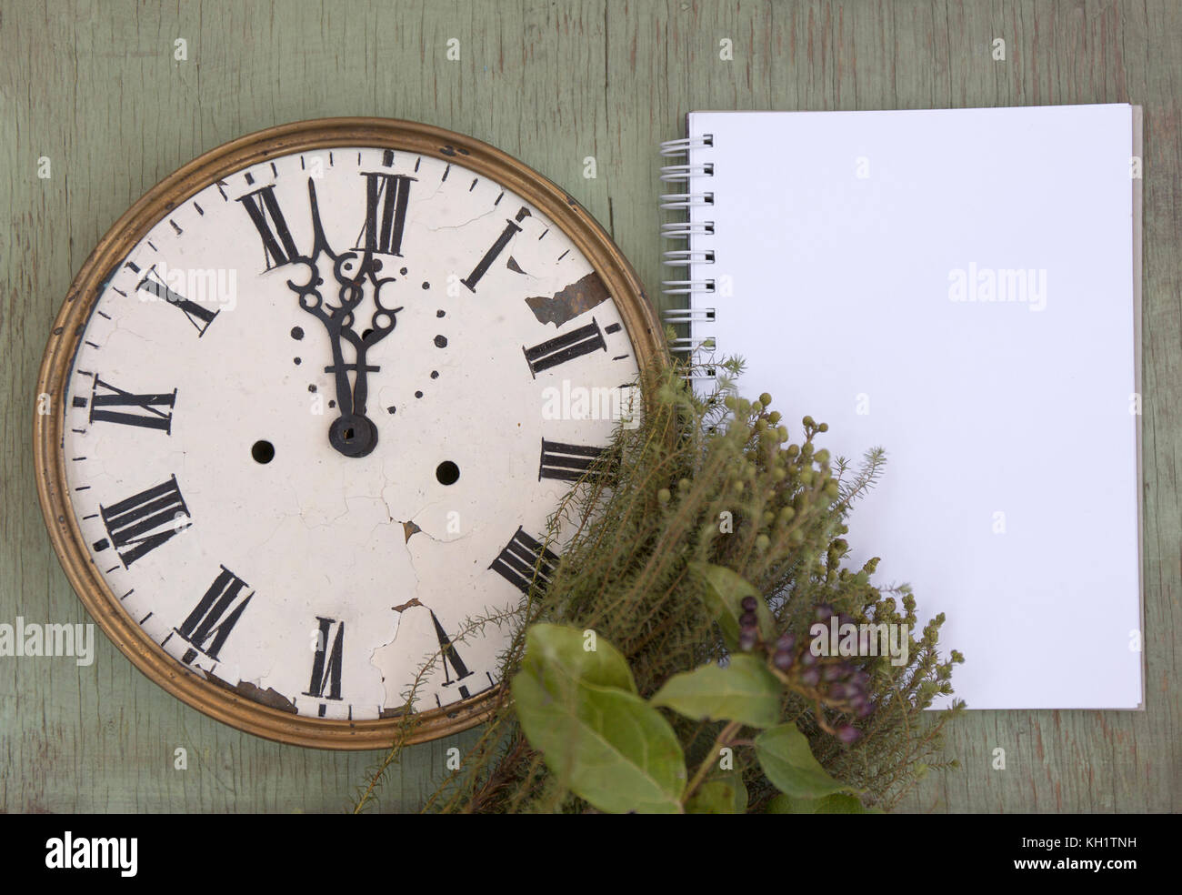Old clock and blank notepad on the green wood background. New year ...