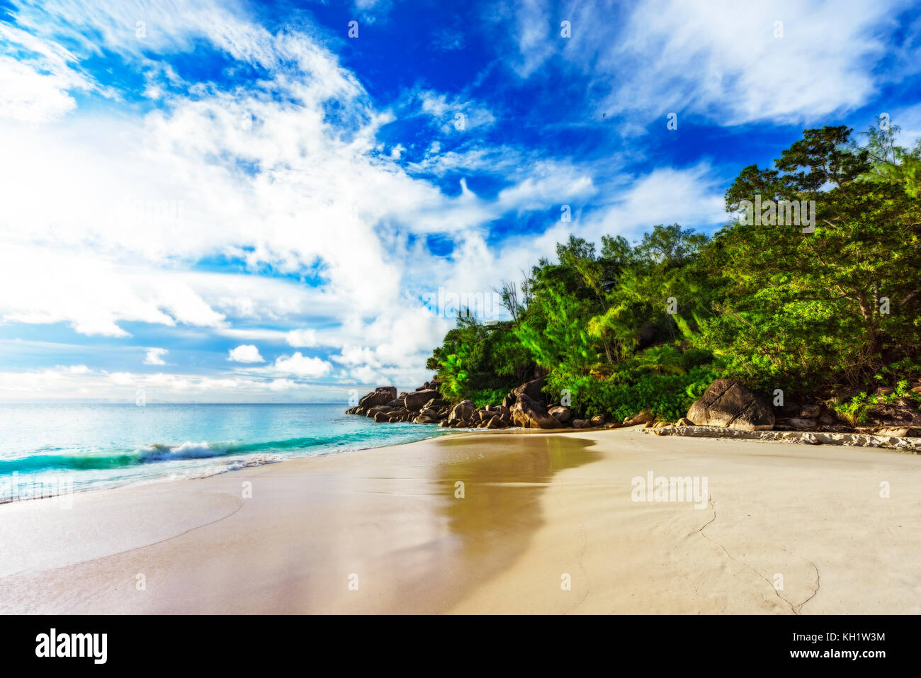 sunny day on paradise beach with big granite rocks, turquoise water, white sand and palm trees at anse georgette,praslin seychelles Stock Photo