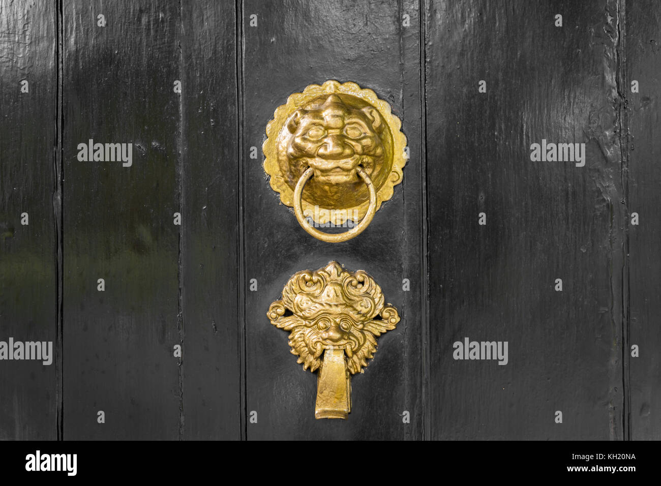 Antique gold or brass door knocker ornate on black door Stock Photo