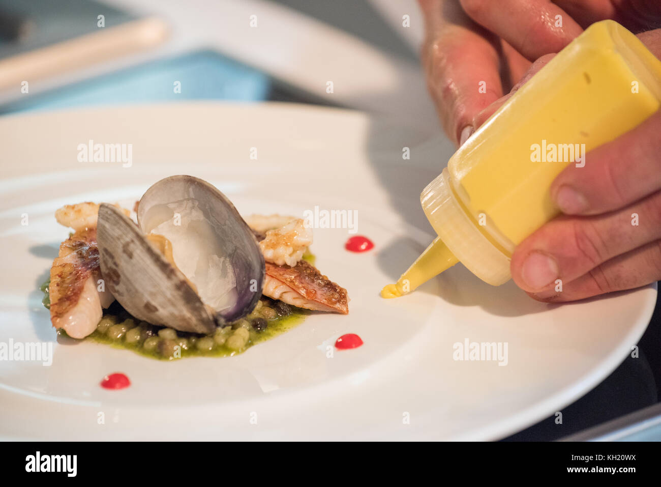 A chef delicately places a spot of sauce on a seafood dish Stock Photo