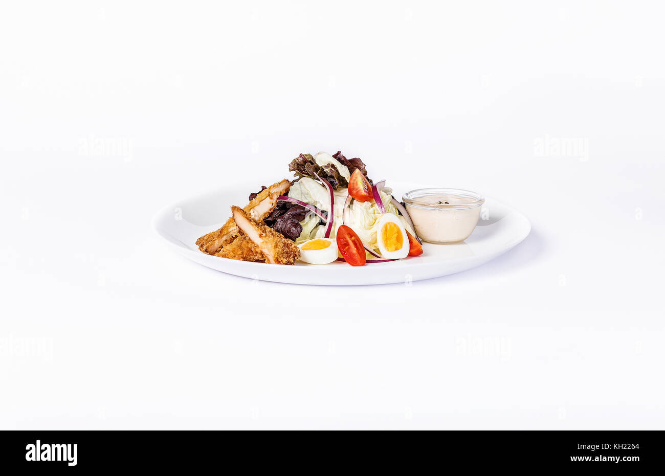 Pan-Asian salad, vegetables and eggs with fried chicken. On a white plate on a white background. Stock Photo
