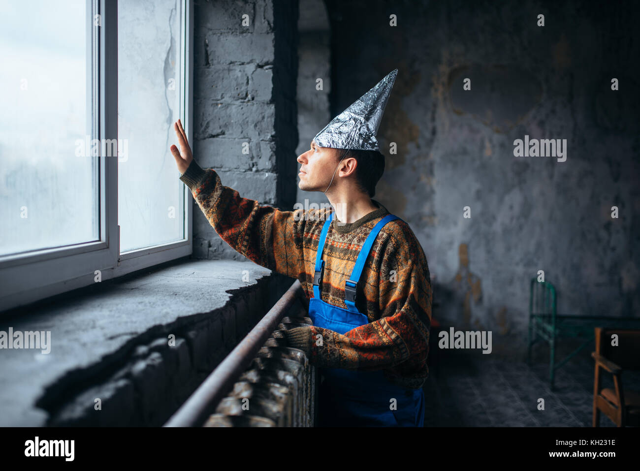 Man in tinfoil cap looking out the window, UFO Stock Photo