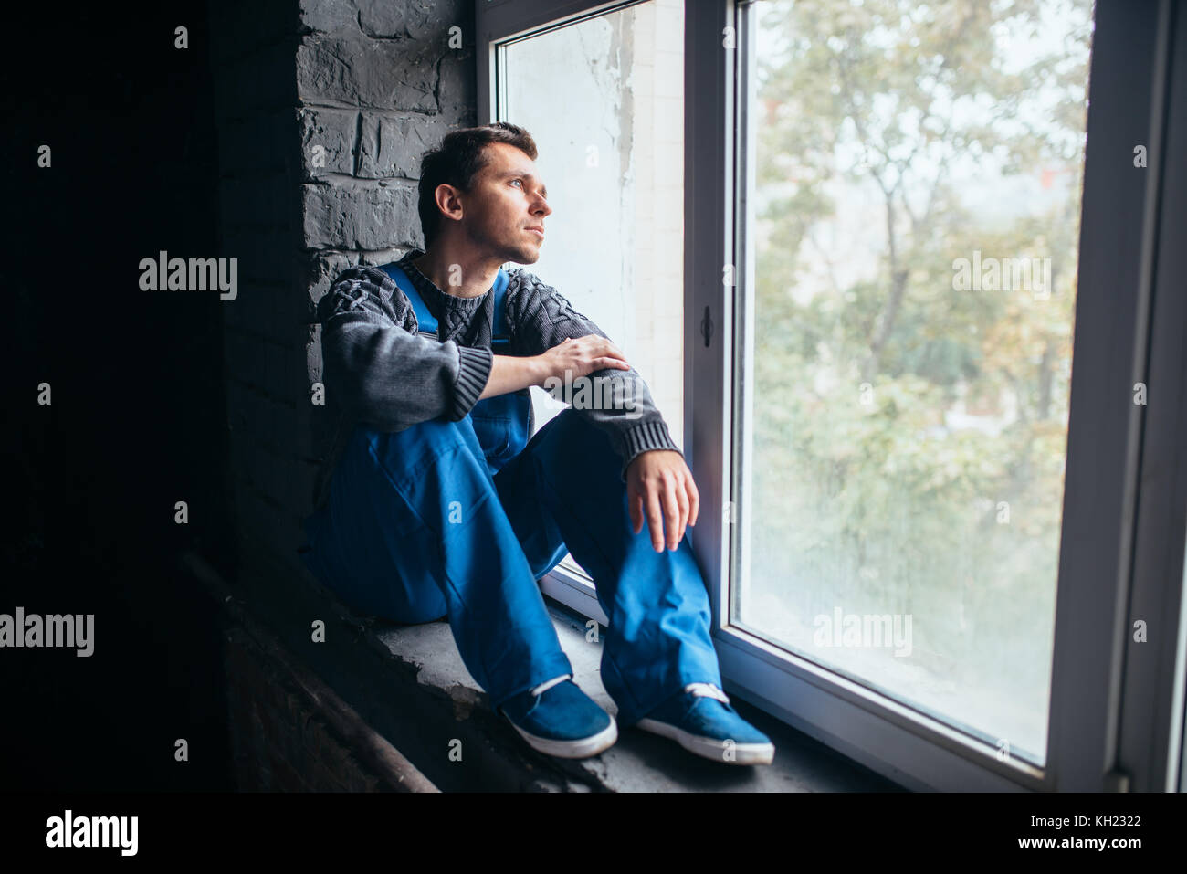 Depressed man sitting on the window sill, psycho Stock Photo