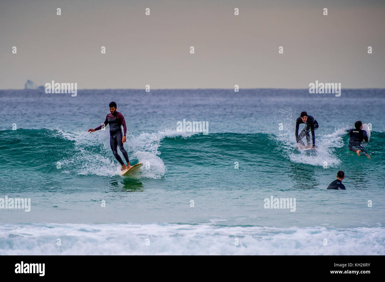 Multiple surfers ride a wave at Sydney's iconic Bondi Beach, NSW, Australia Stock Photo