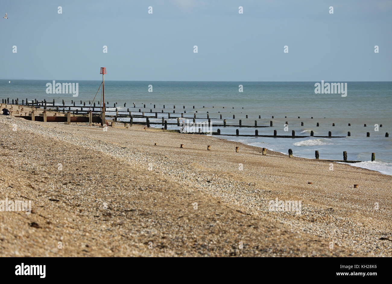 View along deserted Bognor beach, southern England, on a sunny, winter day. Shows wooden breakwater structures installed to prevent coastal erosion. Stock Photo
