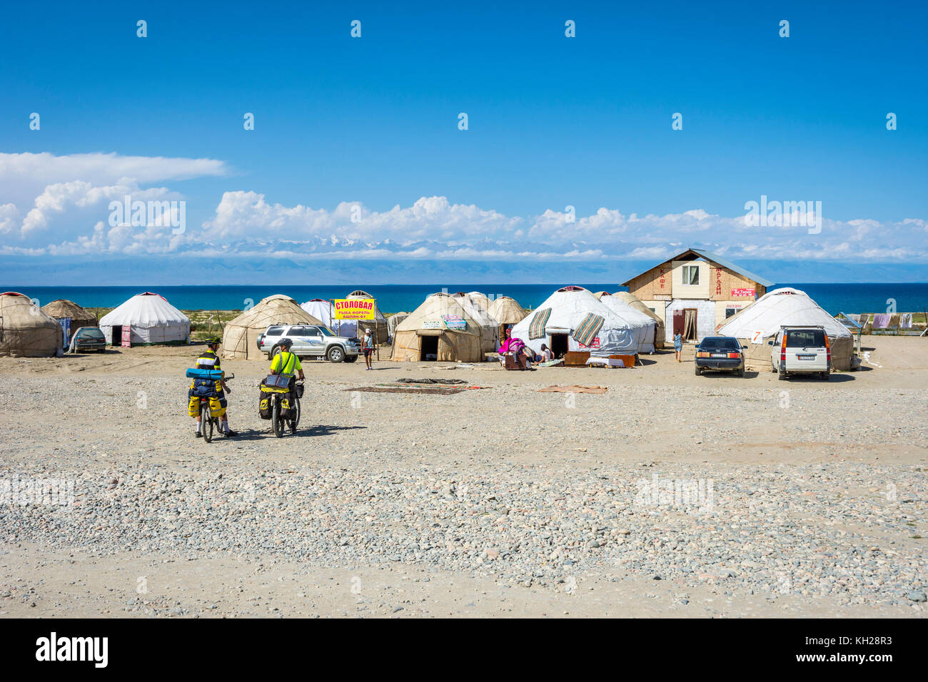 KYZYL TOO, KYRGYZSTAN - AUGUST 8: Two bikers by the yurts next to Karakol lake and the mountains behind. August 2016 Stock Photo