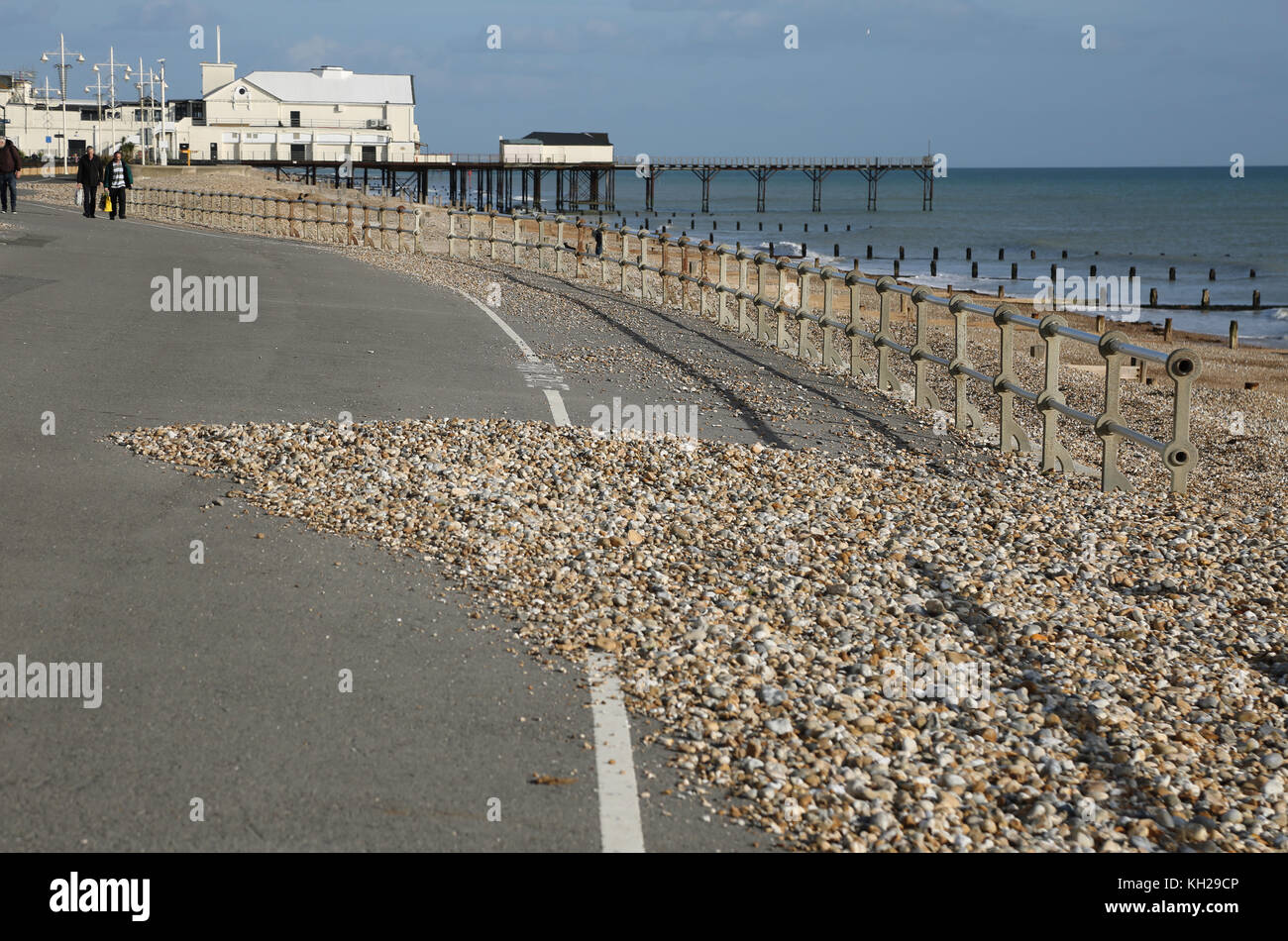 shingle overflows onto the seafront promenade in Bognor Regis, Sussex, UK, following stormy winter weather. Shows Bognor Pier in background. Stock Photo
