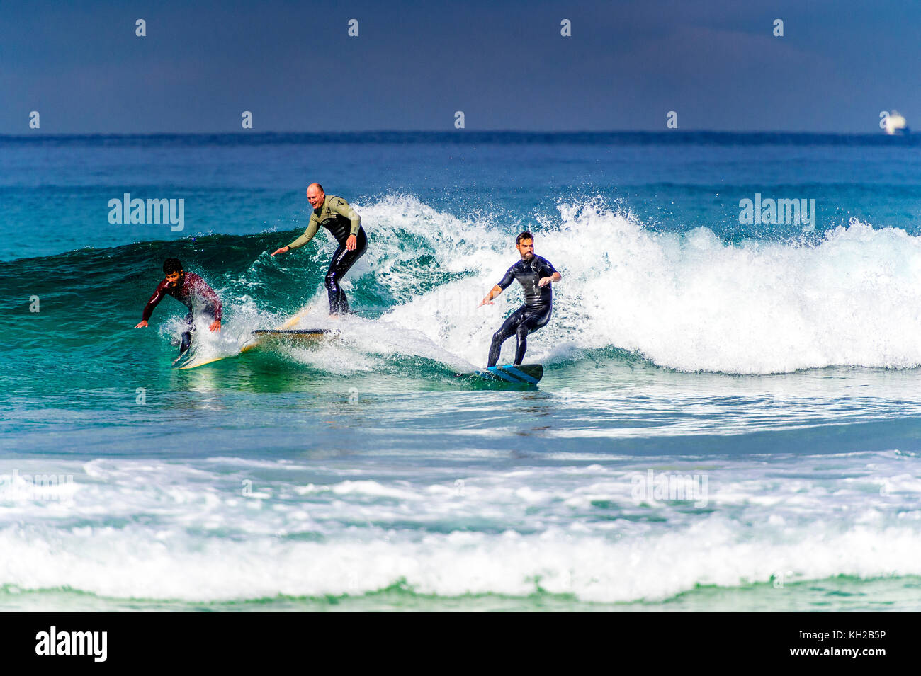 Multiple surfers ride a wave at Sydney's iconic Bondi Beach, NSW, Australia Stock Photo