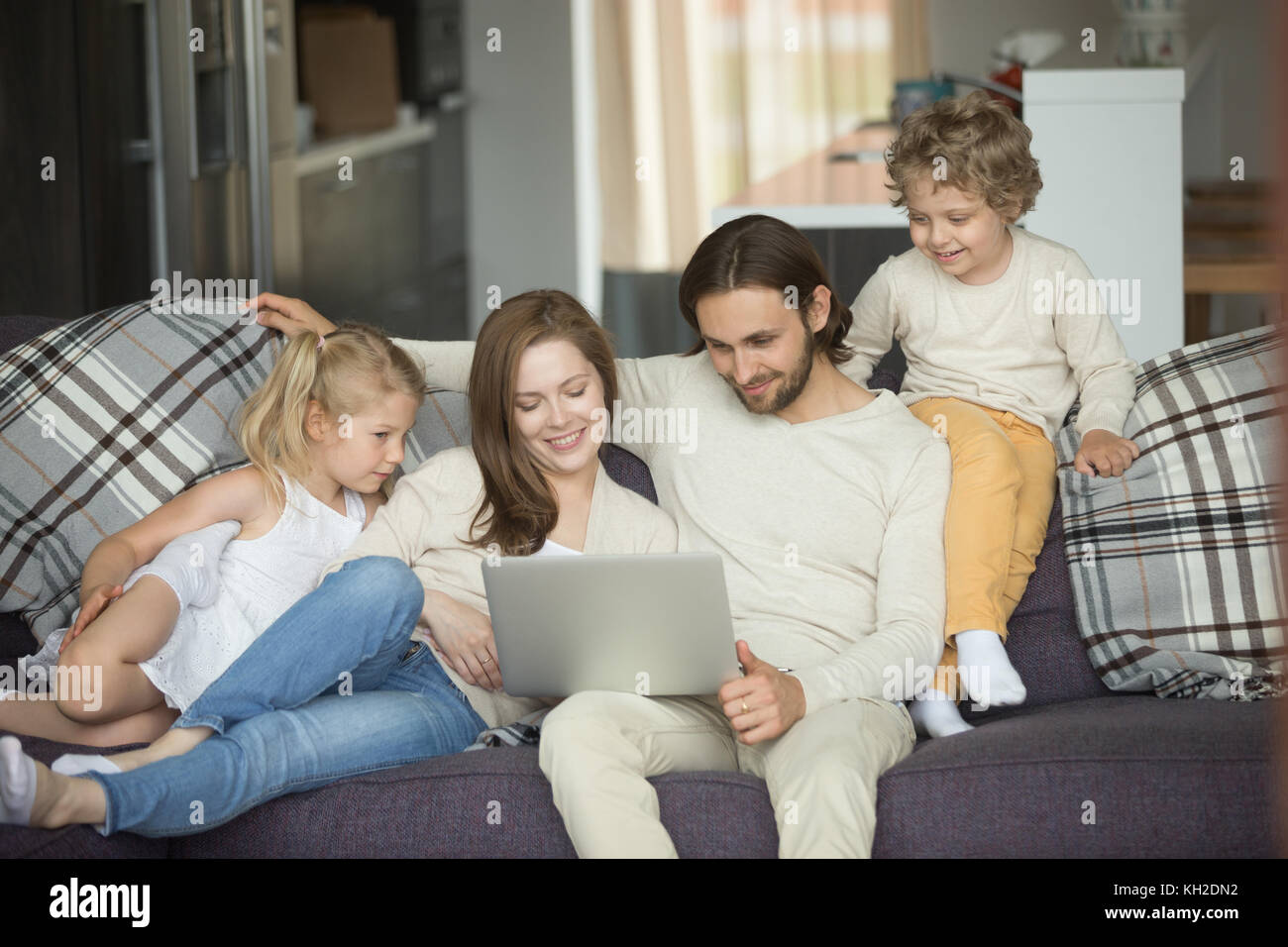 Happy family with kids using laptop sitting on sofa at home, smiling ...