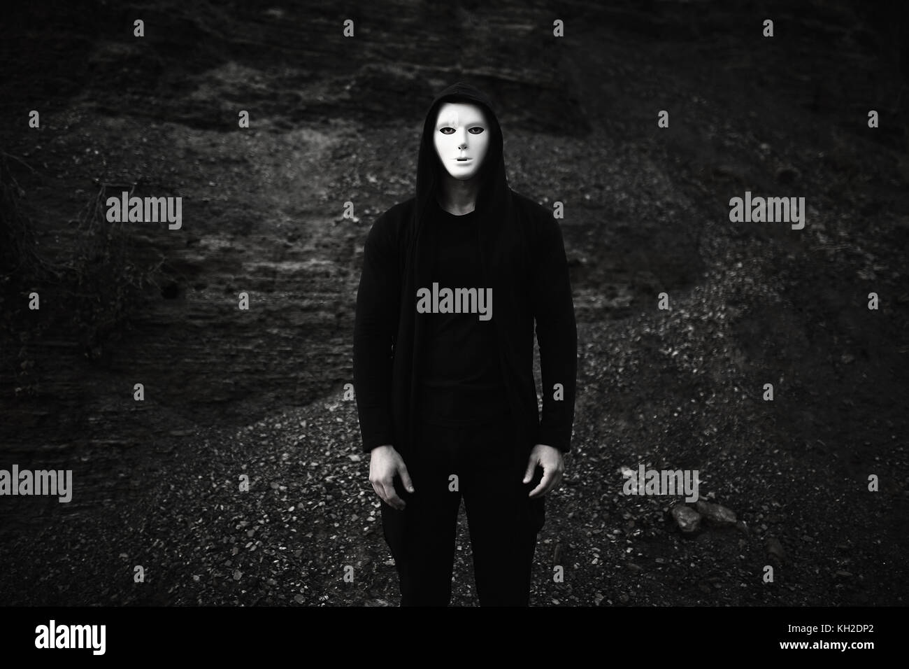 Portrait of man in black hoodie wearing white anonymous mask. Stock Photo