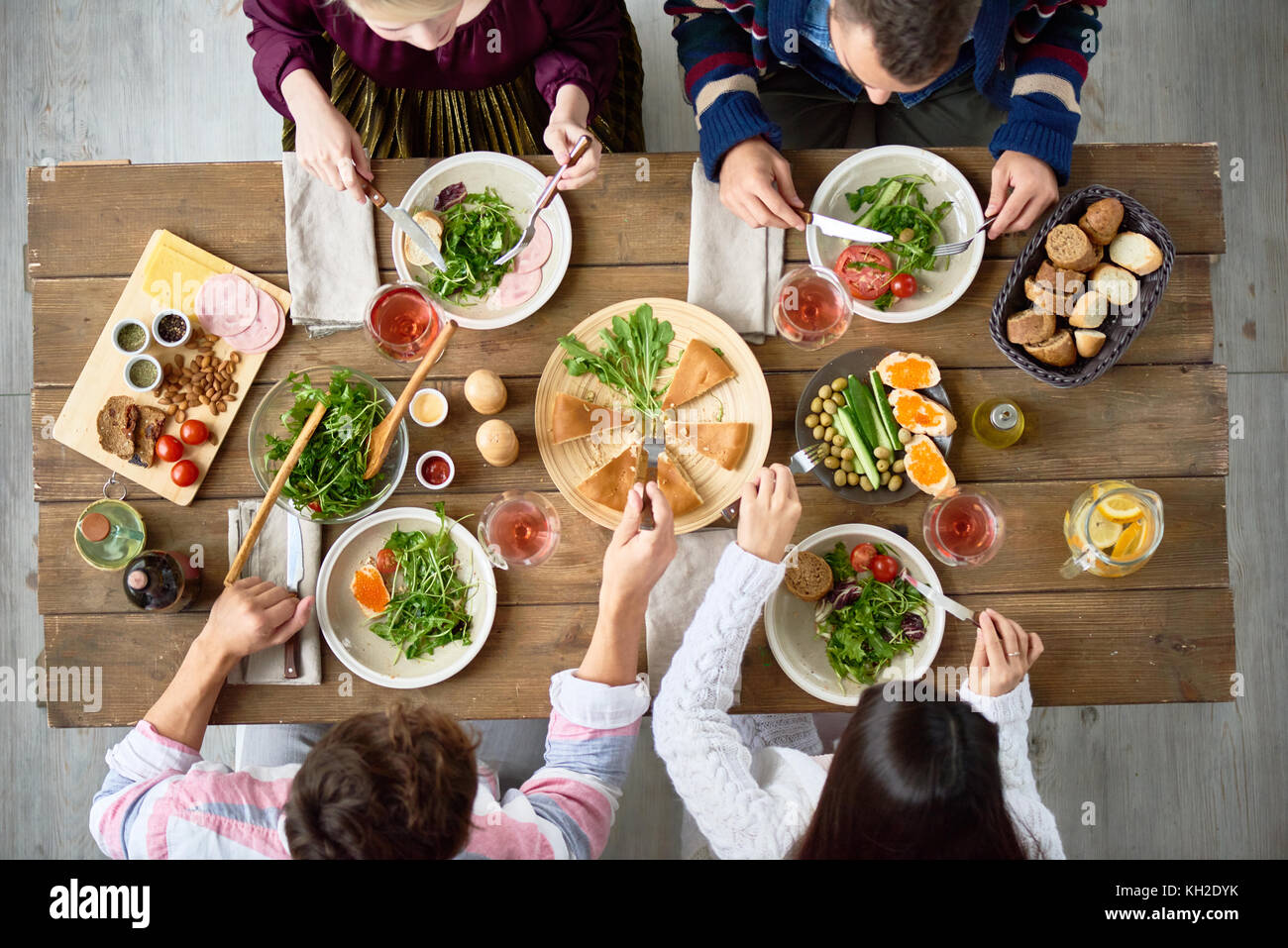 Top view of four friends eating at festive dinner table with delicious