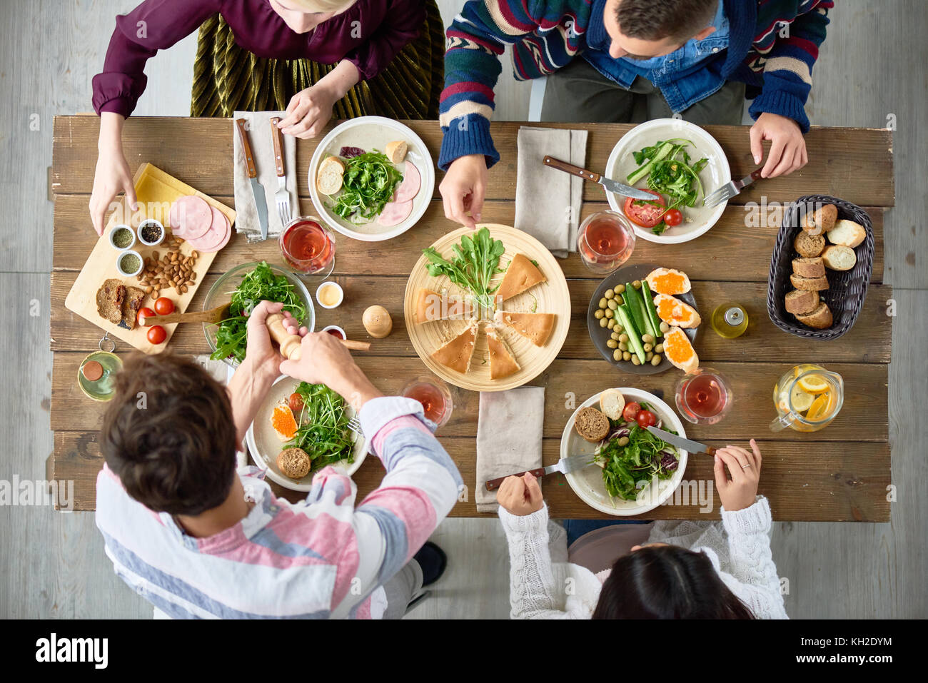Above view of four people eating delicious food at festive dinner table