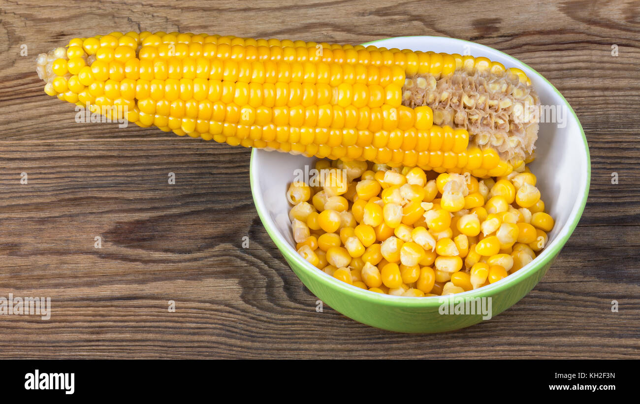 Partially empty corncob and heap of boiled maize. Yellow corn grains in ...