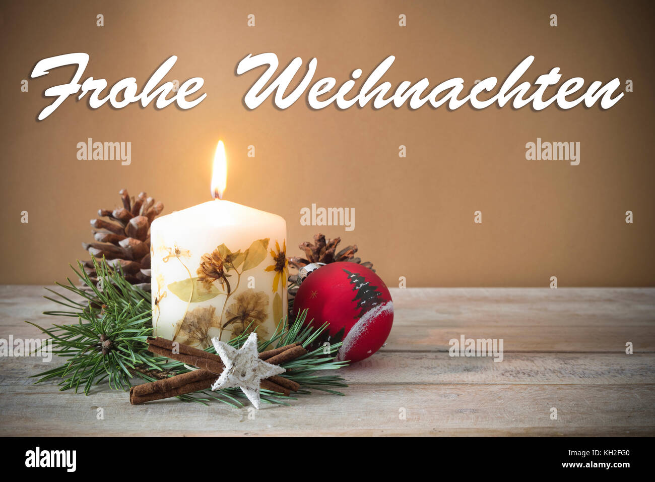 Christmas decoration with candle, pine, bauble, with text in German 'Frohe Weihnachten' in wooden background. Stock Photo