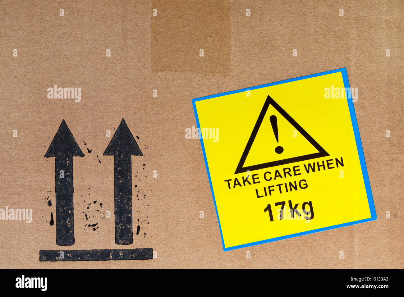 Take care when lifting 17kg yellow sticker label stuck on cardboard box and keep upright arrows symbol Stock Photo