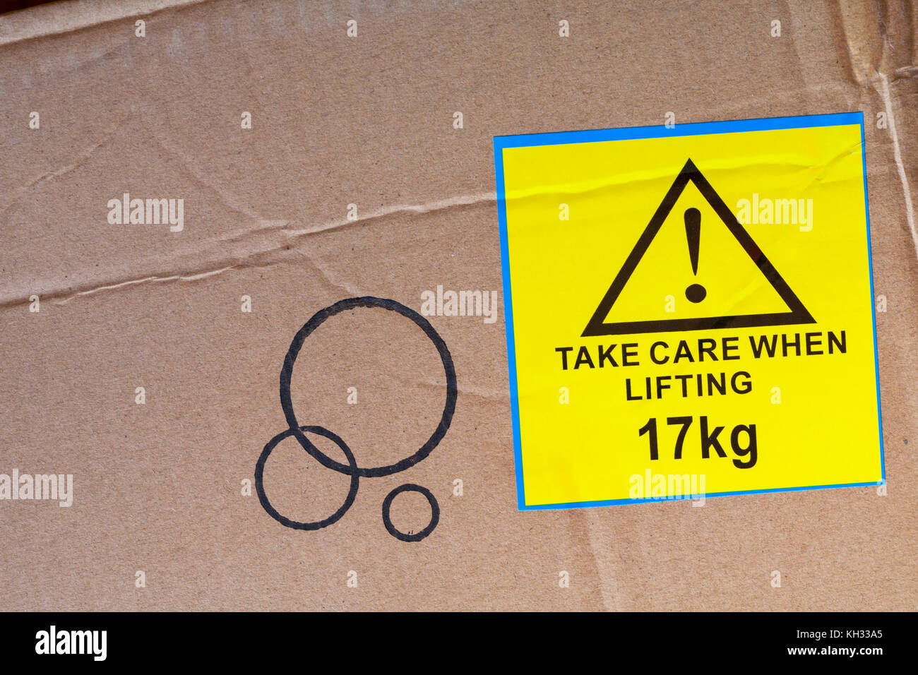 Take care when lifting 17kg yellow sticker label stuck on cardboard box Stock Photo