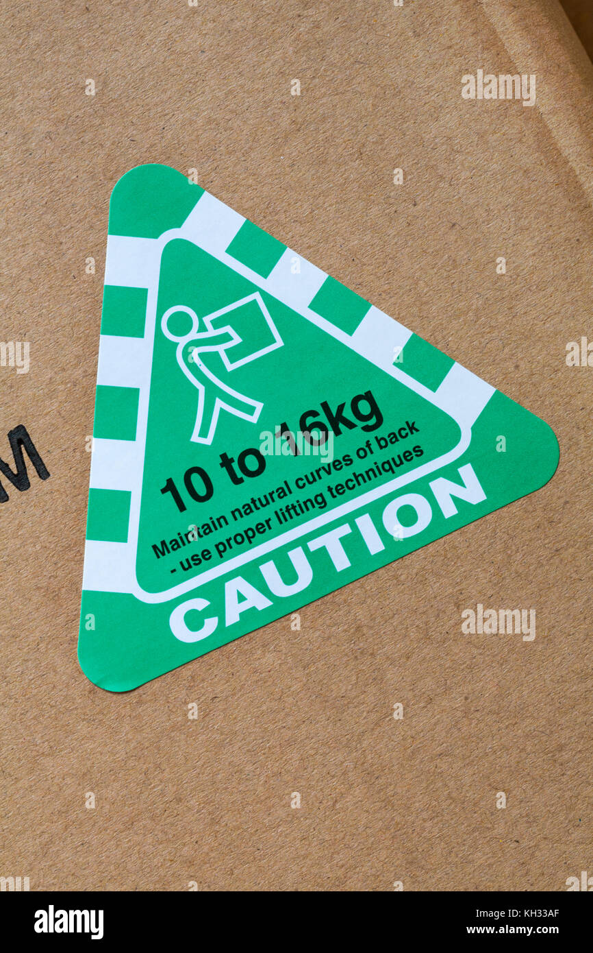 caution maintain natural curves of back - use proper lifting techniques 10 to 16kg sticker stuck on cardboard box Stock Photo