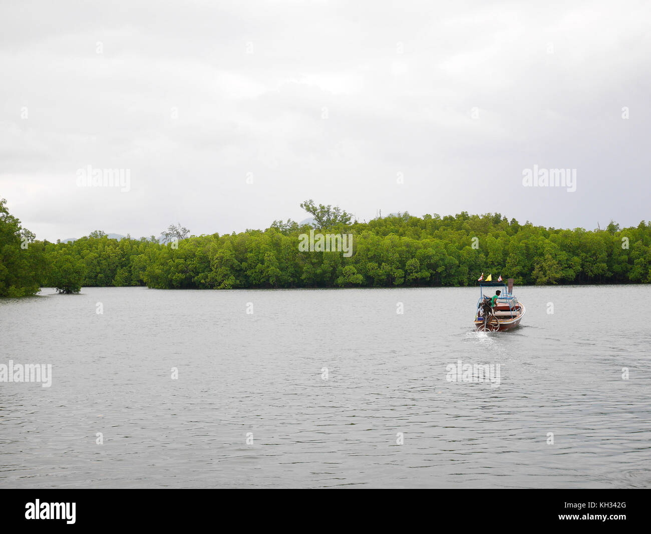 Boat on the shallow ocean under cloudy sky Stock Photo - Alamy
