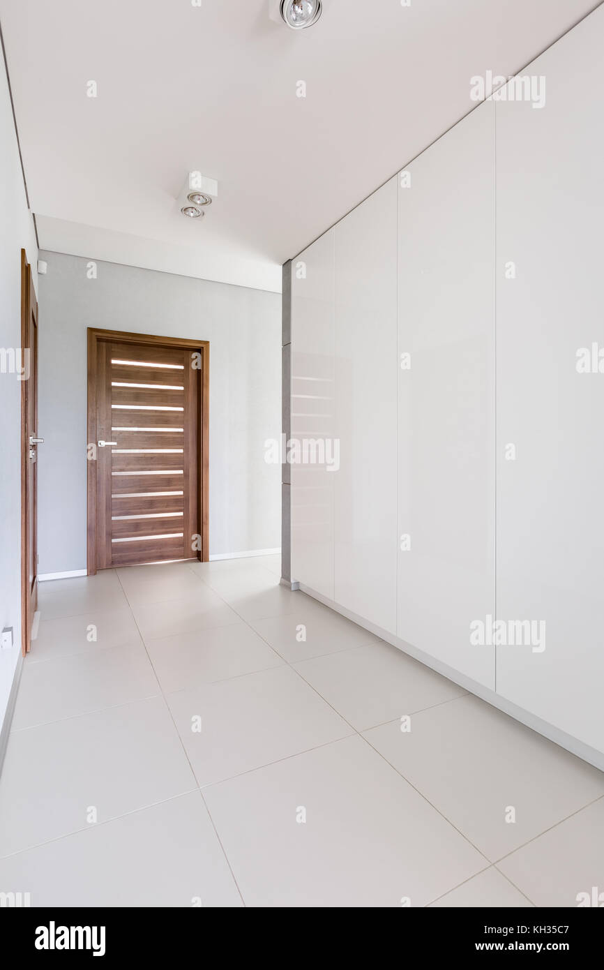 Home interior with white hallway and wooden door Stock Photo - Alamy