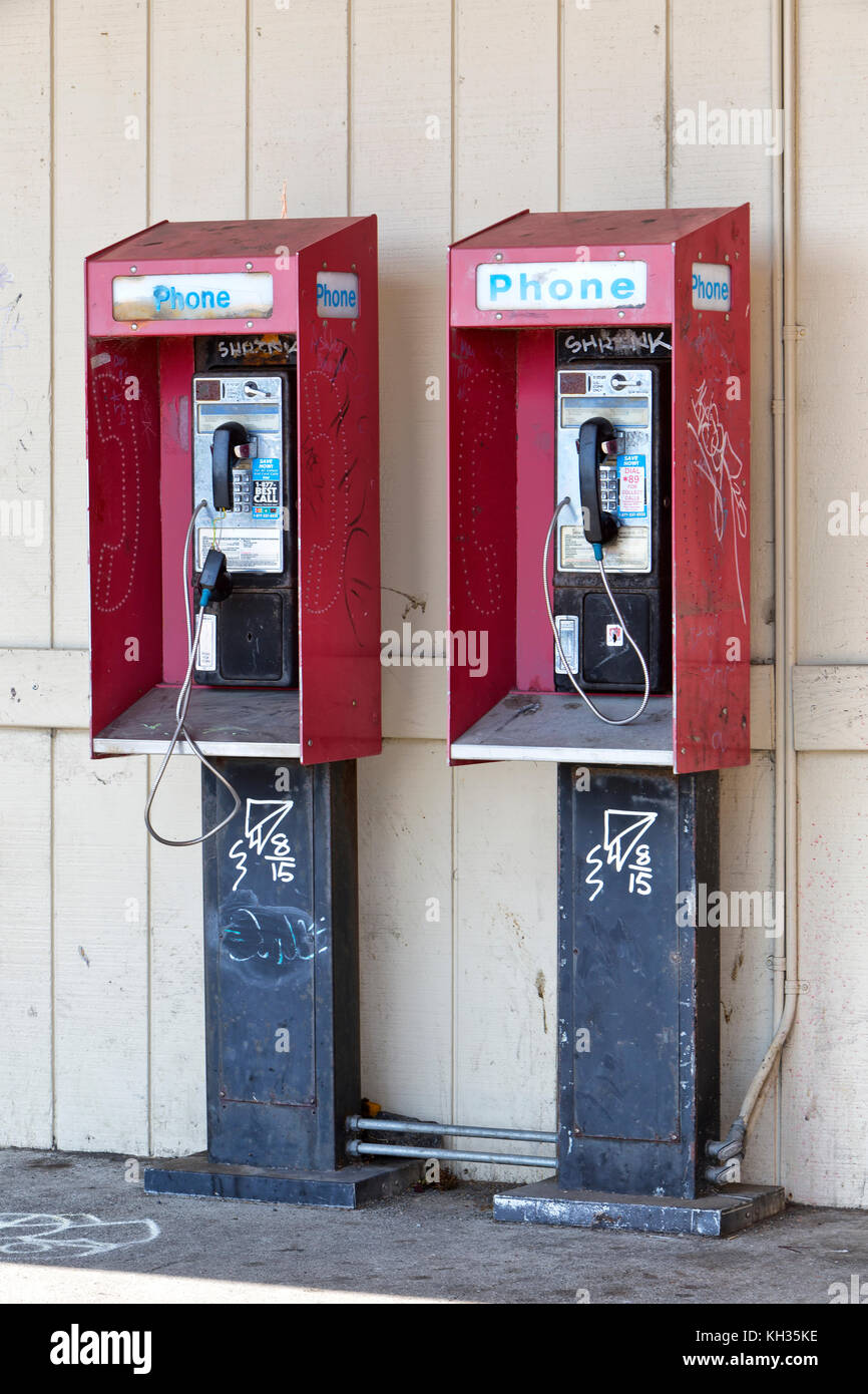 Abandoned coin operated public pay telephones with coin release slot, graffiti. Stock Photo