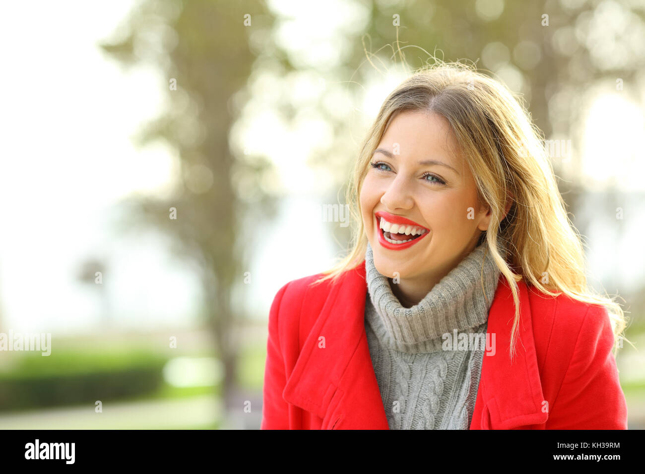 Funny woman wearing a red jacket laughing outside in a park in winter Stock Photo