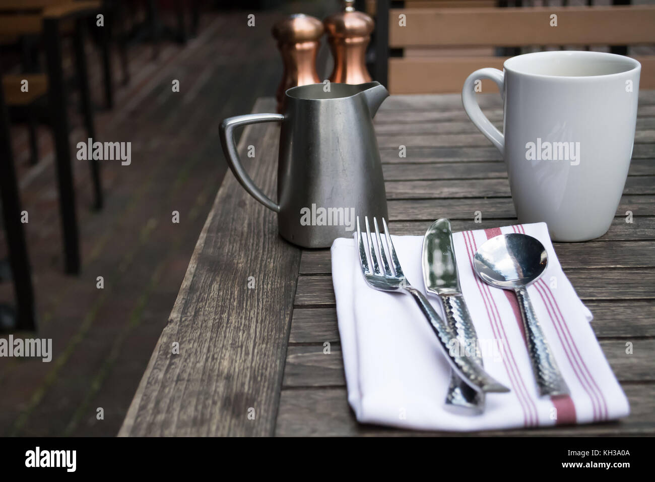 Casual outdoor dining in a cafe in a downtown historic Alexandria Virginia. Traditional place setting with a cloth napkin, pewter cream pitcher Stock Photo