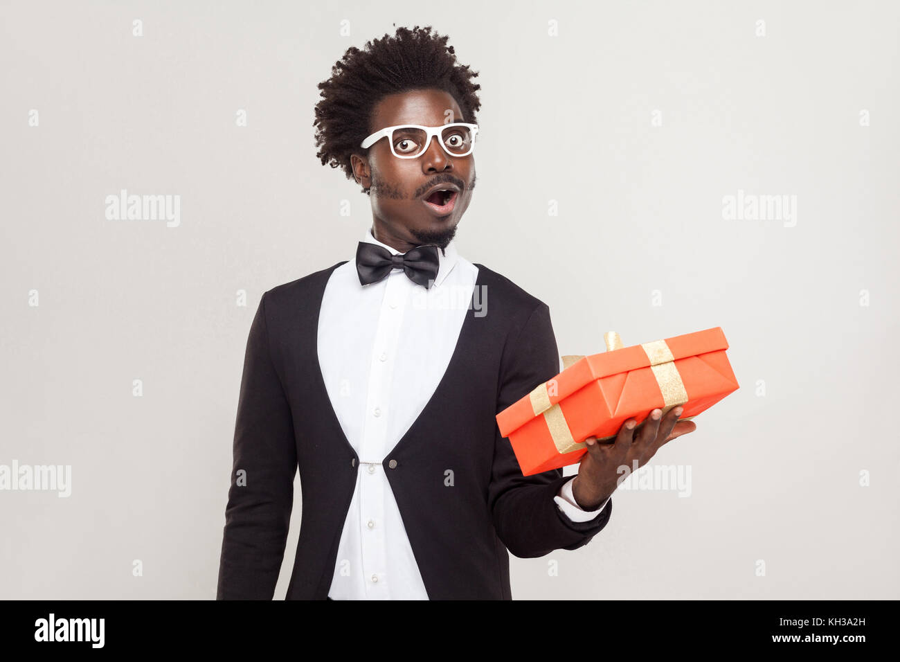 Man Raging Out Gift Amazement man holding gift box and shocked. Studio shot, gray ...