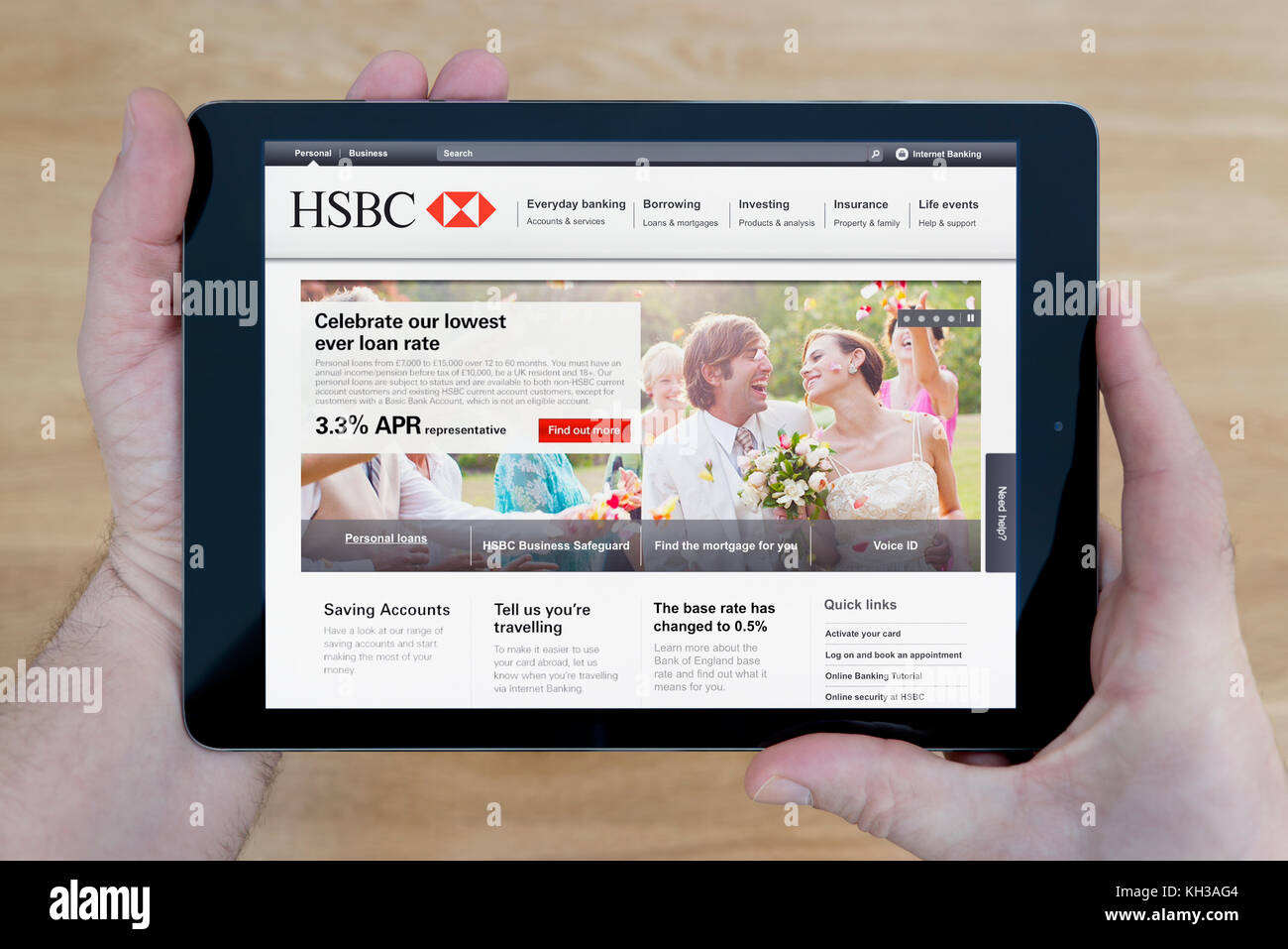 A man looks at the HSBC bank website on his iPad tablet device, shot against a wooden table top background (Editorial use only) Stock Photo