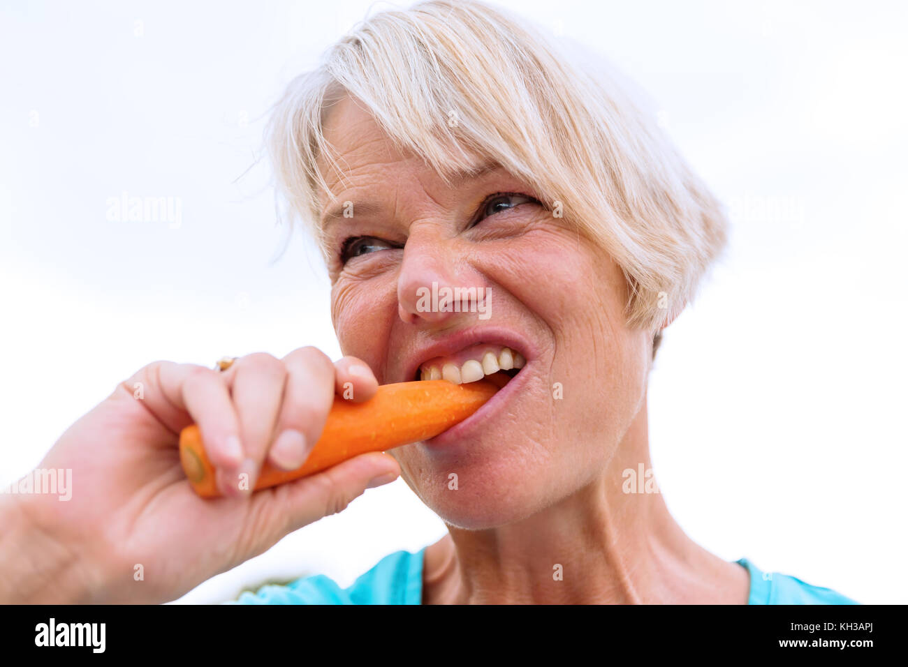 picture of a mature woman who bites in a carrot Stock Photo