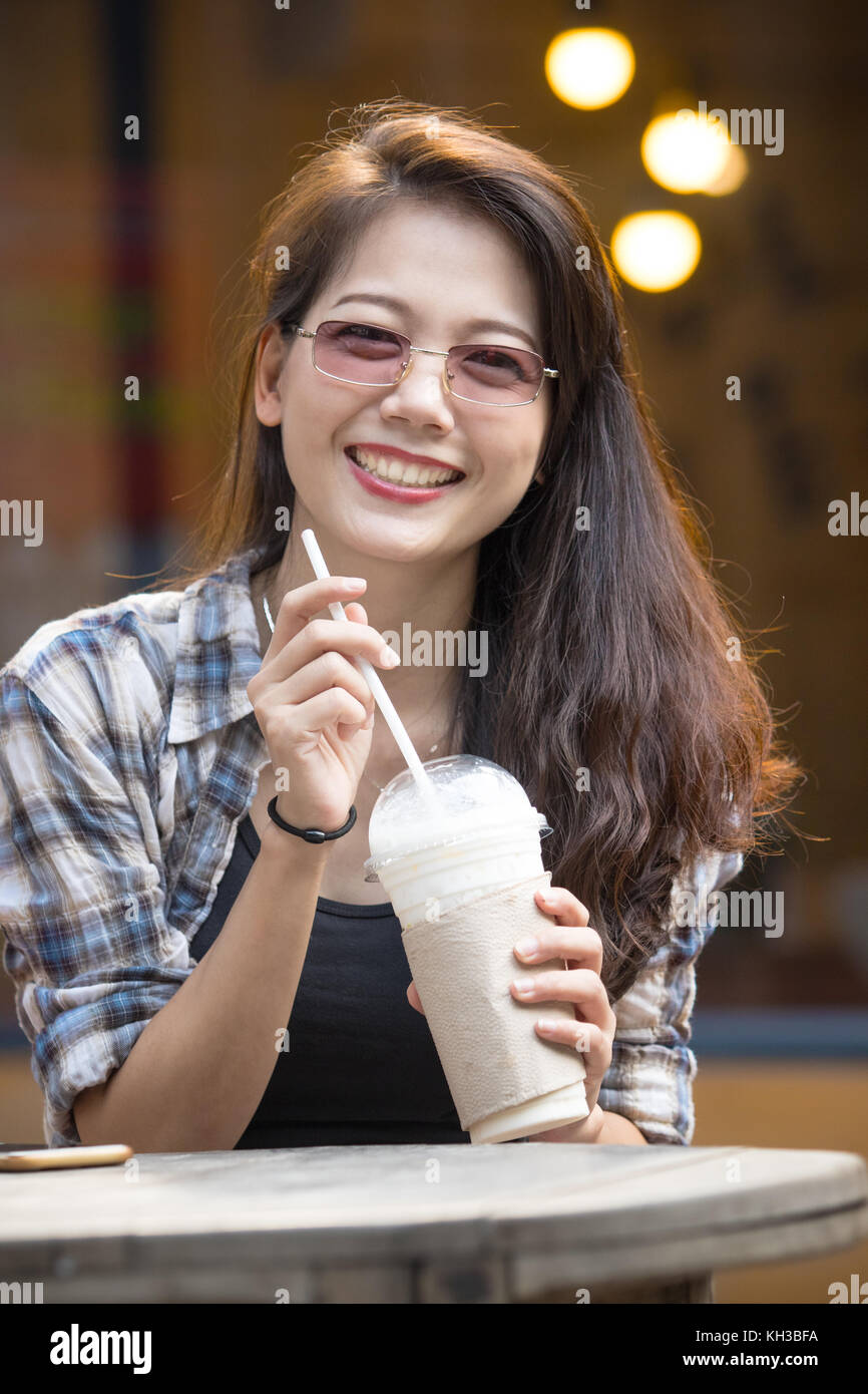 toothy smiling face happiness emotion of younger asian woman with cool drink bottle in hand Stock Photo
