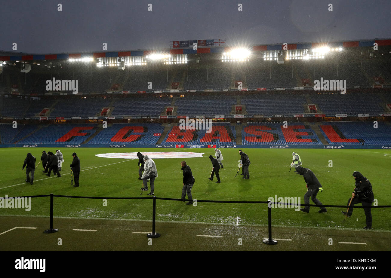 Ground staff use pitchforks to help drain the rainwater from the pitch before the FIFA World Cup Qualifying second leg match at St Jakob Park, Basel. Stock Photo