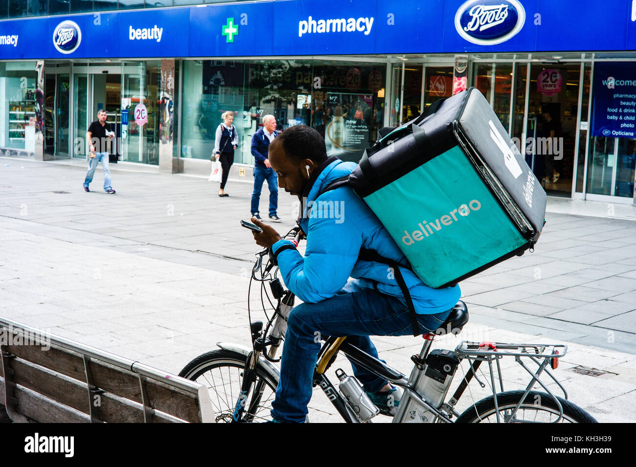 A delivery agent for  the food delivery company Deliveroo studies his mobile telephone for his latest instructions. Stock Photo