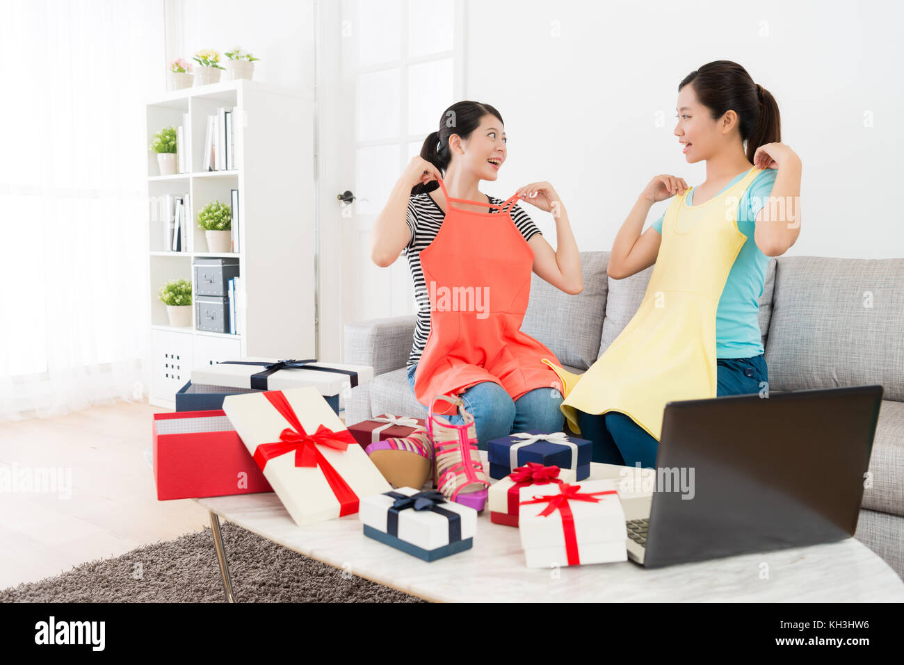 happy smiling sisters showing new clothing dress for friend and looking ...