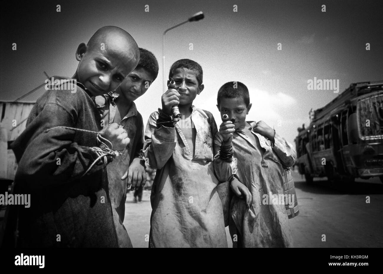 Popularely called 'Garbage children', they are afghan refugee children who go to de dumps to collect any sellable objecs, in this case a group of four are holding magnets in their hand as pistols which are used to find metal objecs between the city debries in Peshawar, Pakistan. Date: 08/2000. Photo: Xabier Mikel Laburu. Stock Photo
