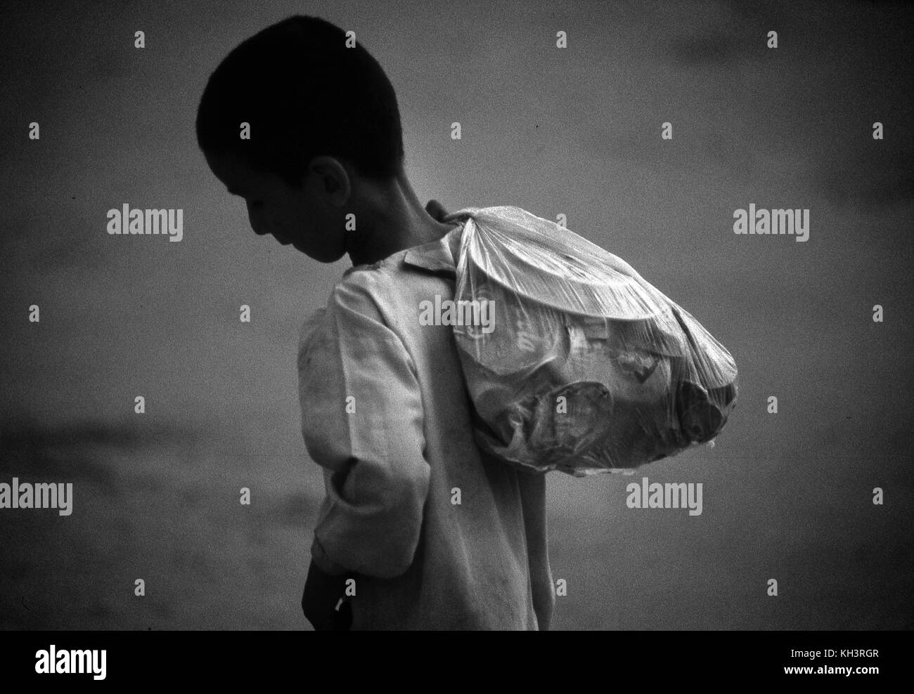 Popularely called 'Garbage children', they are afghan refugee children who go to de dumps to collect any sellable objecs, in this case it is a child which is carrying the tin objects he found in the fruit market dump in Rawalpindi, Pakistan. Date: 08/2000. Photo: Xabier Mikel Laburu. Stock Photo