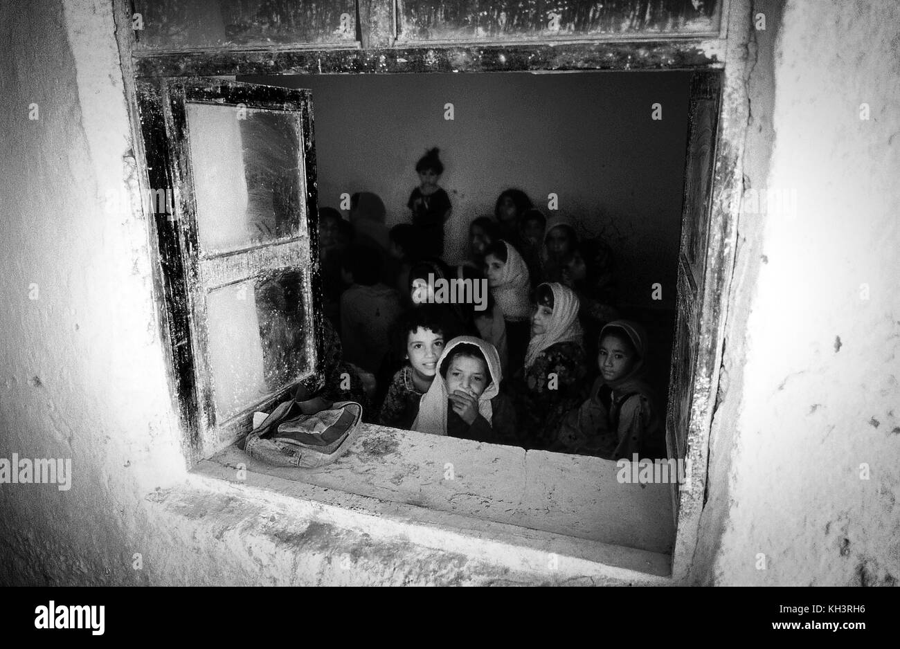 Girls look out of a window from a small school in a refugee camp in Peshawar, Pakistan. Date: 8/2000. Photographer: Xabier Mikel Laburu Stock Photo