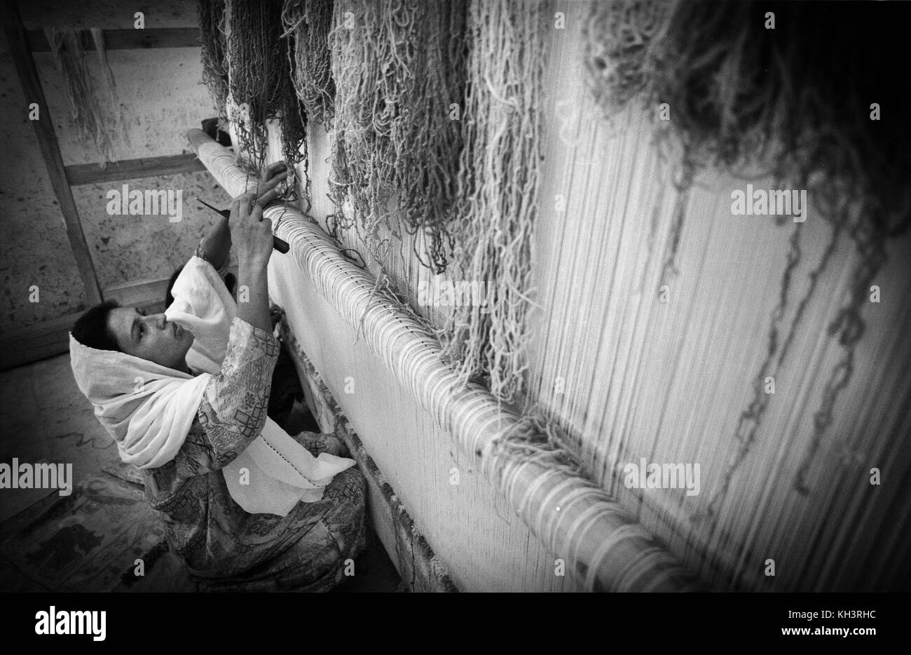 An afghan refugee women weaving a carpet in the refugee camp of Jalozai, Peshawar, Pakistan. Date: 08/2000. Photo: Xabier Mikel Laburu. Stock Photo