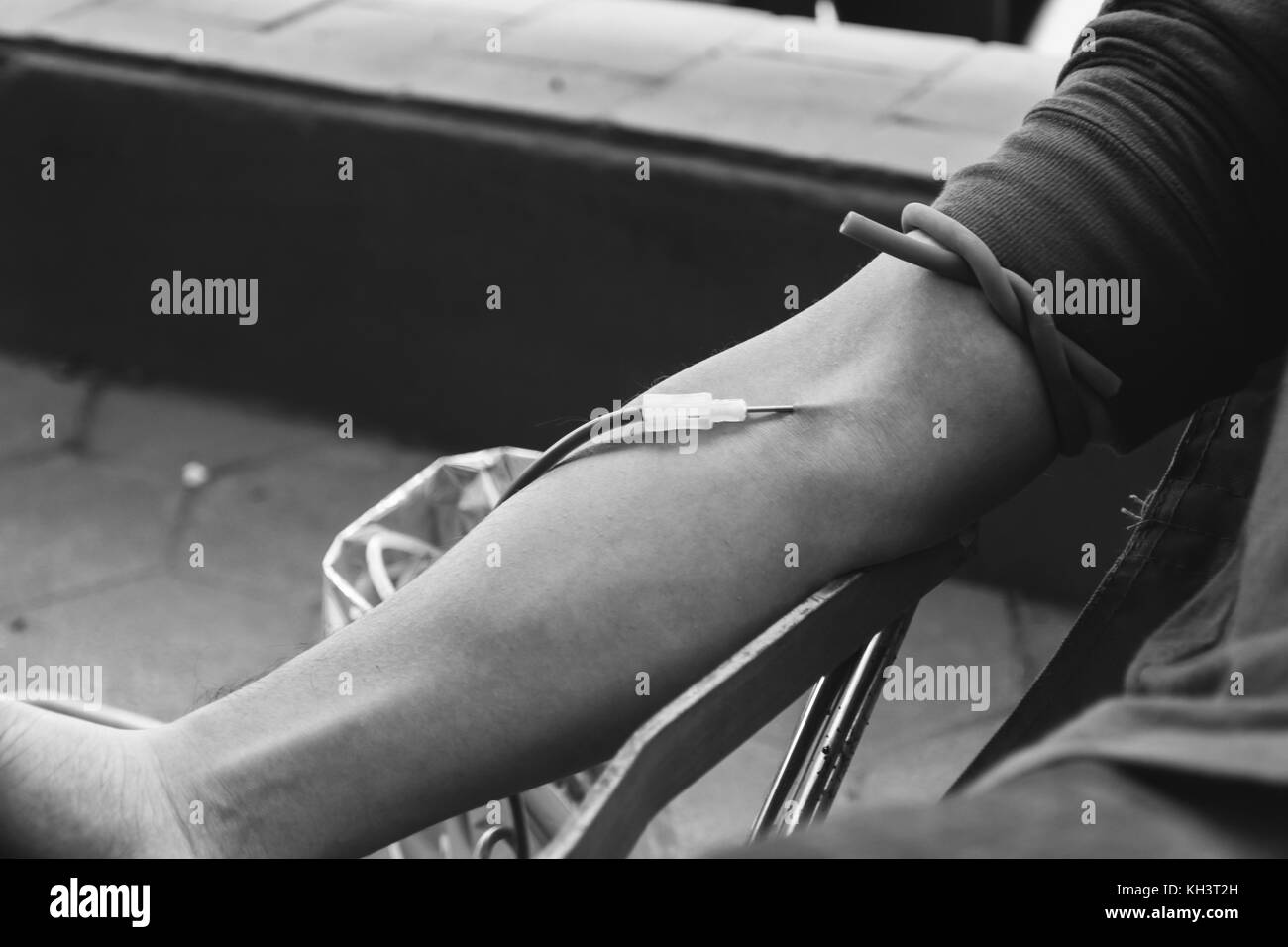 close up on arm of blood donor while donating blood on black and white tone Stock Photo