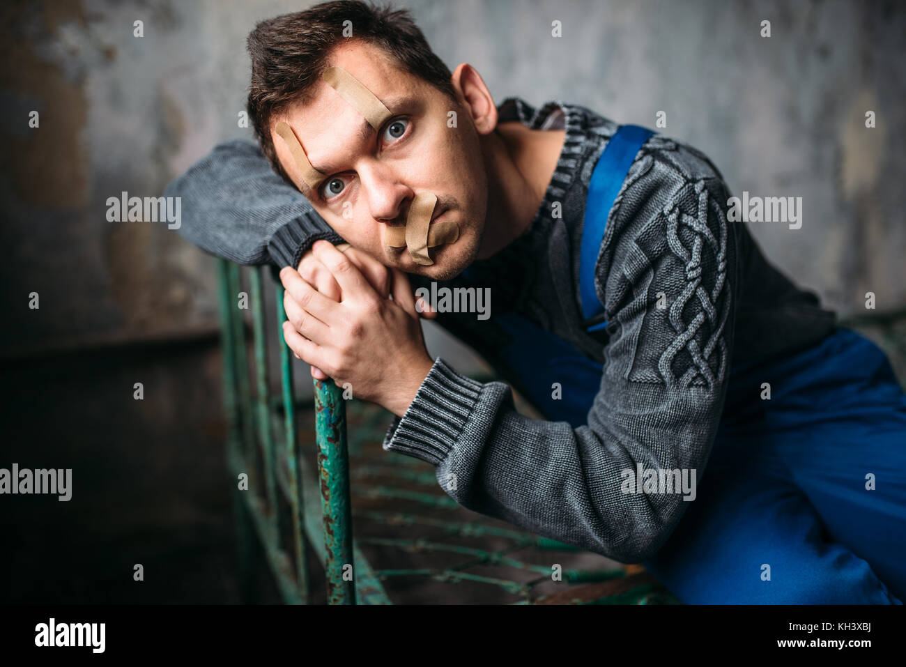 Madman, eyelids and mouth sealed with plaster Stock Photo